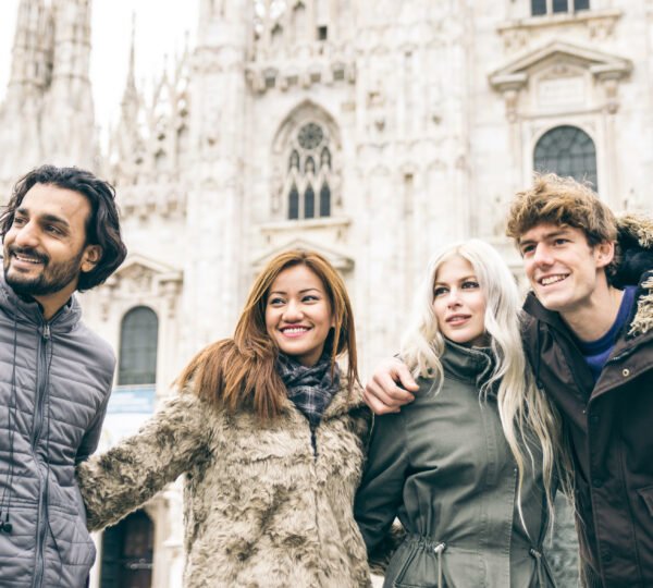 Group of friends walking in Milan city center. Different ethnicity people portrait with Duomo in the background
