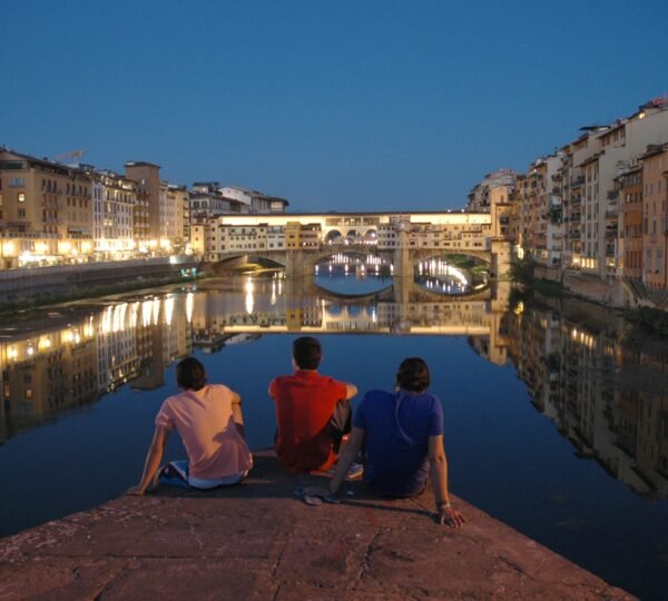 A horizontal shot of three friends enjoying the beautiful view of buildings with lights and the water